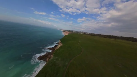 Cliffside road winds through grassy hills overlooking ocean waves Stock Footage 340225219