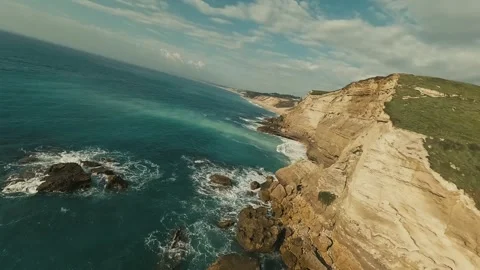 Cliffside road winds through grassy hills overlooking ocean waves Stock Footage 340226132