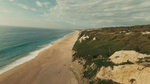 Cliffside road winds through grassy hills overlooking ocean waves Stock Footage 340226510