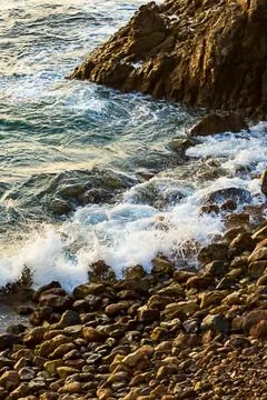 Cliffside view of ocean wave breaking  on rocky shoreline Stock Photos