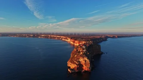 Cliffside view with wind turbines and ocean during sunset in coastal area Stock Footage 336546033