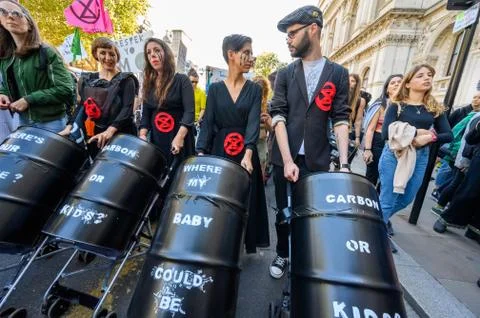 Climate Change protesters with face paint and pushing oil barrels in stroller Stock Photos