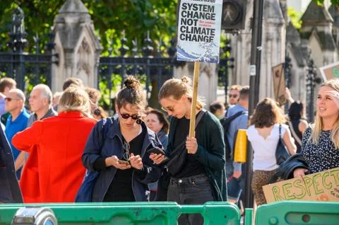 Climate Change protesters using smartphones and holding protest placards at a Stock Photos