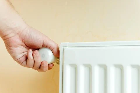 Climate optimism and climate Control . A man switches the temperature on the 库存照片