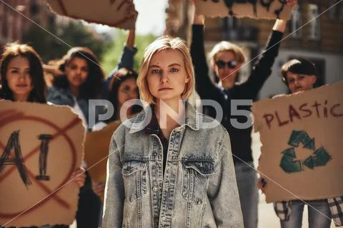Climate strike. Young woman in casual wear protesting with group of activists Stock Photos