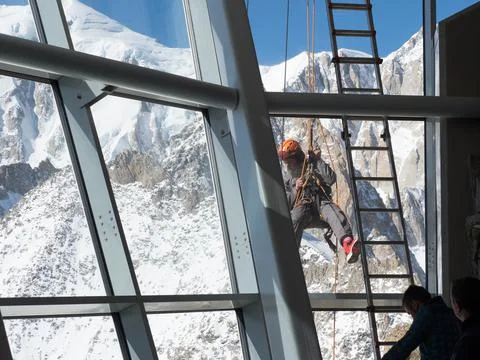 A climber abseils outside a viewing window at Mont Blanc cable car to work  Stock Photos