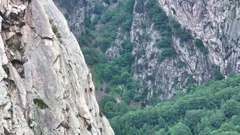 Climber ascending cliff face in mountain valley Stock Footage 289676216