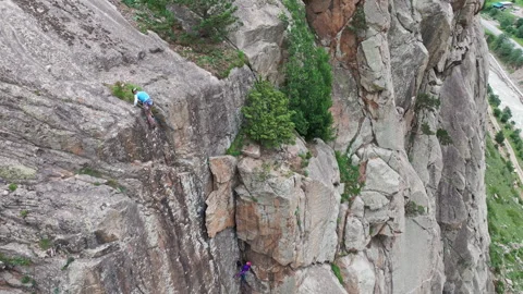 Climber ascending steep rock face with belayer below Stock Footage 289660657