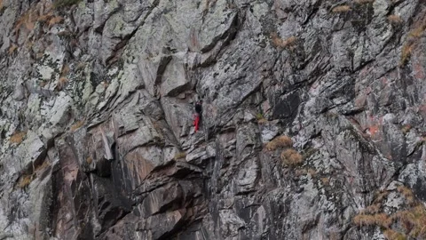 Climber ascends rocky cliff face, showcasing determination and skill in Stock-Footage 316876267