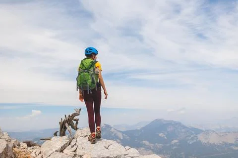 Climber with a backpack and a helmet goes along a mountain path in the mounta Stock Photos