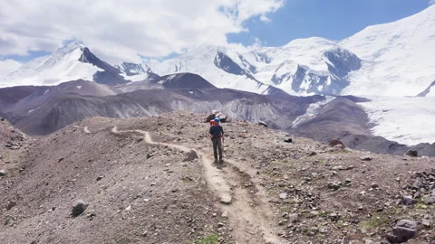 Climber with backpack and trekking poles on Lenin Peak ascent Видео 340110037