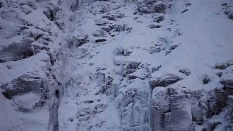 Climber coiling rope and talking to partner on wintry mountain face. Drone, 4K Stock Footage 93175516