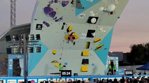 Climber Competes on Outdoor Wall During Evening Rock Climbing Competition Event 스톡 동영상 339240854