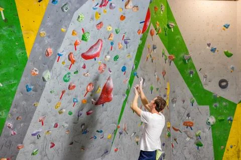 Climber explores and develops a route on a climbing wall in the boulder hall Stock Photos