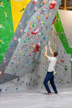 Climber explores and develops a route on a climbing wall in the boulder hall Stock Photos