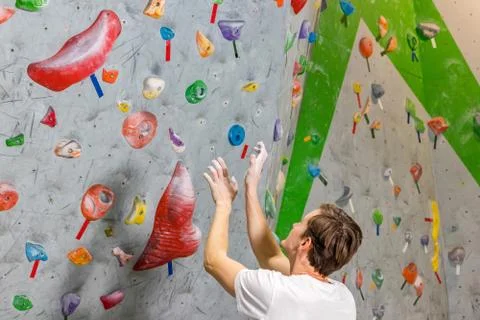 Climber explores and develops a route on a climbing wall in the boulder hall Stock Photos