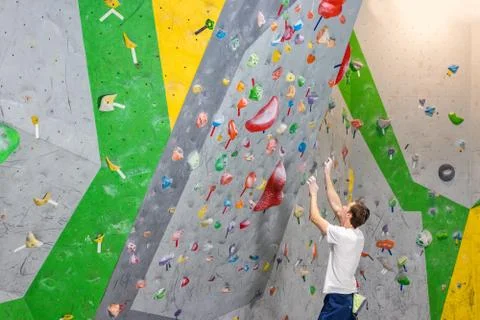 Climber explores and develops a route on a climbing wall in the boulder hall Stock Photos