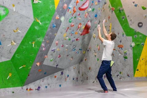 Climber explores and develops a route on a climbing wall in the boulder hall Stock Photos