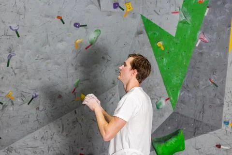 Climber explores and develops a route on a climbing wall in the boulder hall Stock Photos