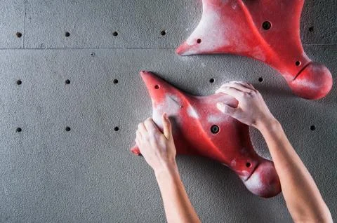 Climber hands holding artificial boulder in climbing gym Stock Photos