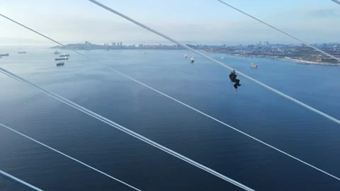 A climber hangs on the bridge cables against the background of Vladivostok Stock Footage 144186755