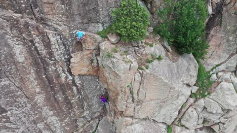 Climber helping another climber climbing cliff 動画素材 289660152