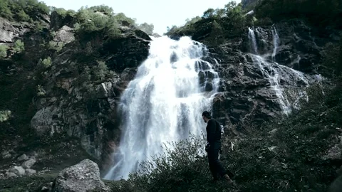 Climber at a huge waterfall among the rocks Stock Footage 138690983