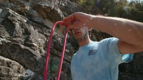 Climber Inspecting Red Rope Before Ascent, a Mixture of Concentration and Stock Footage 272991342