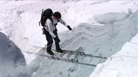 Climber on ladder looking down at crevasse 库存影片 22226496