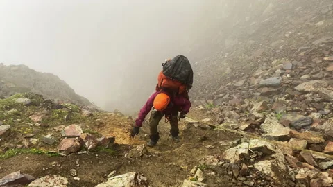 Climber with a large backpack climbs the rope uphill along the trail Stock Footage 157966069