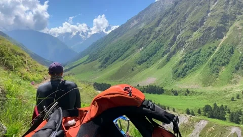 A climber with a large backpack sits on the grass and drinks tea Video stock 135322948