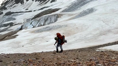 Climber with a large backpack walks along a snowy ice path Stock Footage 135515776