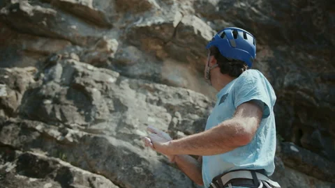 Climber man clap his hands with magnesium. Slow Motion. A male rock climber is Stock Footage 272991574