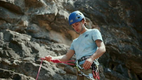 Climber man preparing for climbing up the rocky wall rift by checking rope Stock Footage 273485103