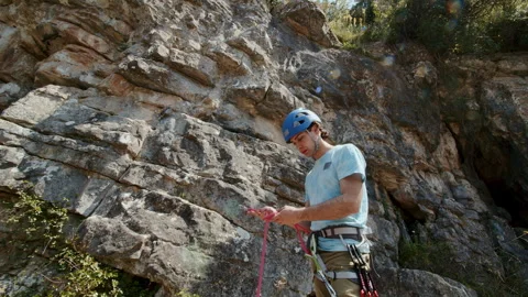 Climber man preparing for climbing up the rocky wall rift by checking rope Stock Footage 273485131