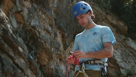 Climber man preparing for climbing up the rocky wall rift by checking rope Stock Footage 273518451