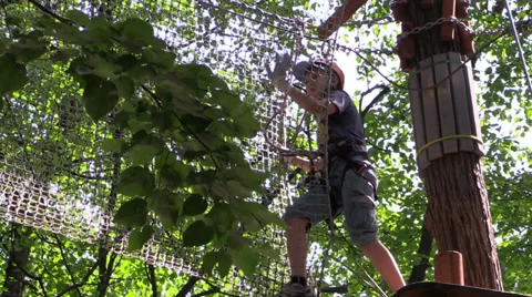 Climber move the ladder stretched platform on tree in the amusement rope park. Video stock 39006925