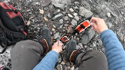 Climber puts climbing crampons on high-altitude mountain boots Stock Footage 208438644