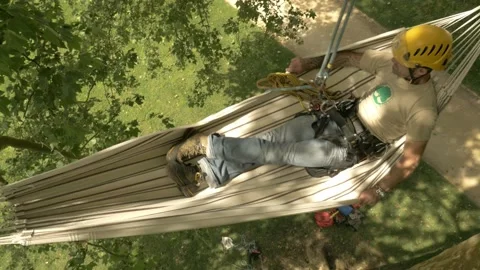 A climber settles in the hamac he fixed on top of a tree, Dordogne - France Vídeos de archivo 230884594