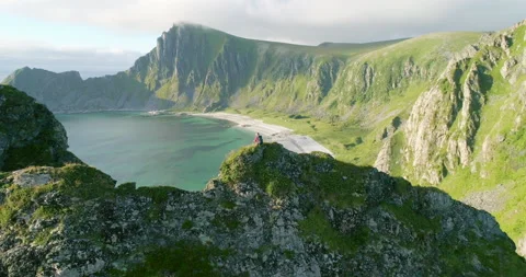 Climber sitting on ridge edge overlooking white arctic beach - parallax Stock Footage 147225700