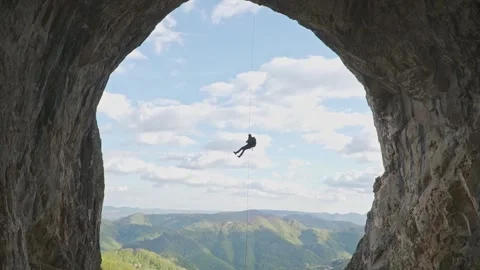 Climber Slowly Descending on Rope Framed by Giant Cave Arch Stock Footage 345632674
