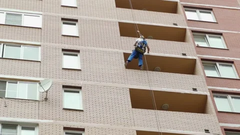 Climber spends repair work on a multi-storey building height Stock Footage 136614582