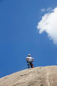 Climber standing on the top of a rock Stock Photos