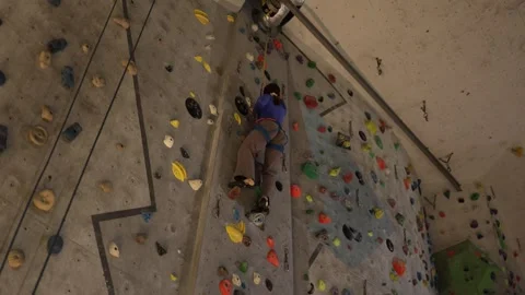 Climber steadily ascends an indoor wall with rope protection. Stock Footage 339287800