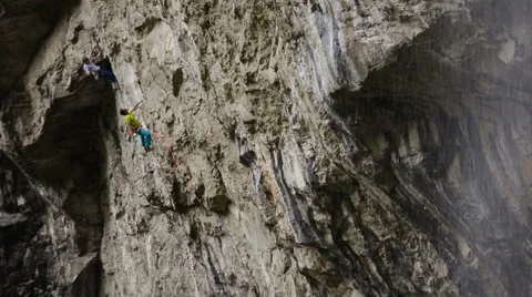 Climber talks to friend while climbing next to waterfall Stock Footage 43810442