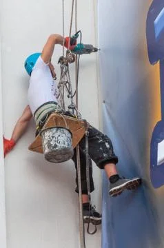 Climber on a vertical wall mounted billboard Stock Photos