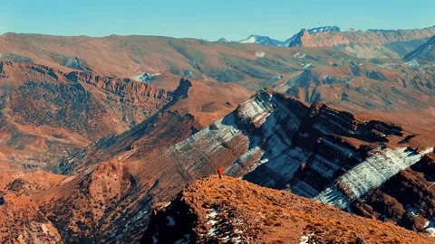 A climber walking on top of a mountain, surrounded by big mountains in The High Stock Footage 345992722