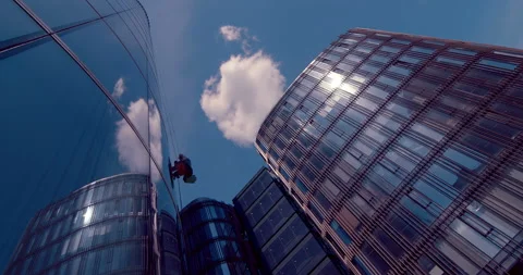 Climber window cleaner doing his job on the glass walls of the business center Stock Footage 119616800