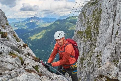 Climber winking towards the camera, while changing lanyards on via ferrata Stock Photos