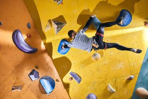Climber without forearm training at yellow climbing wall with artificial rocks Stock Photos